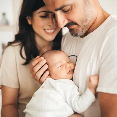 Un hombre cogiendo a un bebé mientras una mujer les mira sonriendo