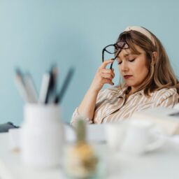 mujer cansada con ojos cerrados y gafas apoyadas en frente