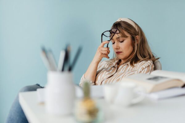mujer cansada con ojos cerrados y gafas apoyadas en frente