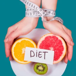 manos atadas con cinta metrica sujetando un plato con tres frutas partidas y un letrero encima que pone en negro y mayusculas diet