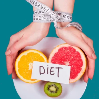 manos atadas con cinta metrica sujetando un plato con tres frutas partidas y un letrero encima que pone en negro y mayusculas diet