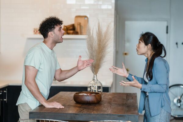 hombre y mujer hablando , gesticulando con las manos, separados por una mesa en medio.