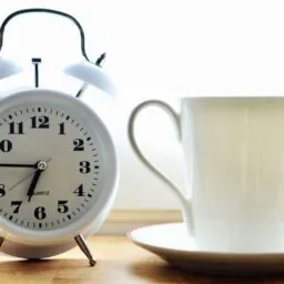 reloj despertador y taza blanca con plato