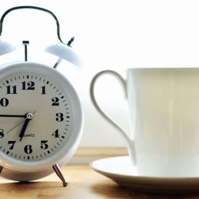 reloj despertador y taza blanca con plato