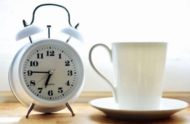 reloj despertador y taza blanca con plato