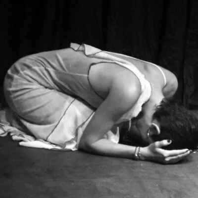 mujer en el suelo encorbada sufriendo con manos tapandose la cara foto en blanco y negro