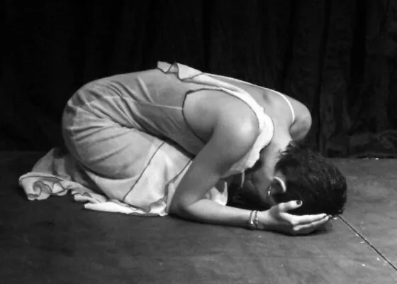 mujer en el suelo encorbada sufriendo con manos tapandose la cara foto en blanco y negro