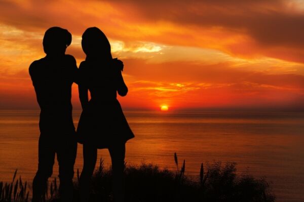silueta pareja hablando entre sí con actitud cercana en atardecer con el mar